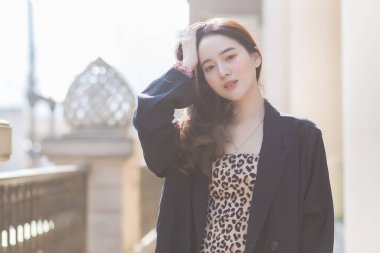 Koyu mavi takım elbiseli Asyalı güzel kadın mutlu görünüyor. Güneşli bir sabahta kahve dükkanının önünde.