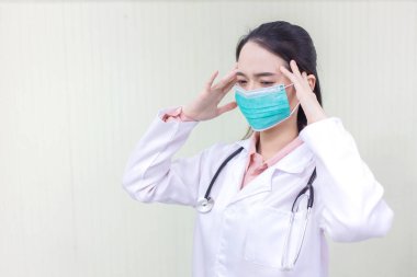 Asyalı kadın doktor muayene odasında maske takıyor ve sağlık hizmetleri, çevre kirliliği PM2.5, yeni normal ve koronavirüs koruma kavramı üzerine kafa yoruyor..