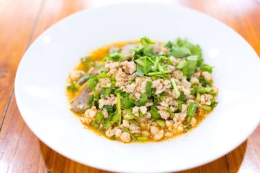 Baharatlı kıymalı domuz salatası Tayland 'ın kuzeydoğusunda geleneksel yemektir. İçinde kıyma, kızarmış pilav, kavrulmuş biber ve Tayland bitkisi var. Beyaz tabağa koymuşlar..