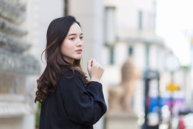 Uzun saçlı, güzel bir Asyalı kadının resmi. Siyah bornozlu güzel bir kadın. Şehirde yürüyor ve dışarı bakıyor..