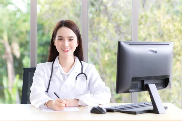 身穿医疗服的亚洲漂亮女医生在医院的办公室里工作 而电脑则放在桌上 — 图库照片