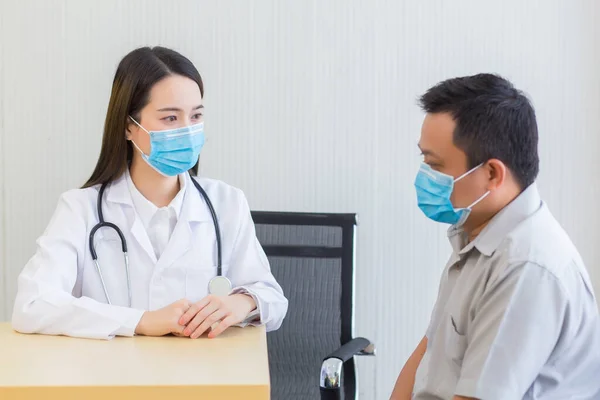 Dokter Wanita Asia Mengajukan Pertanyaan Pasien Dengan Mengenakan Masker Bedah — Stok Foto