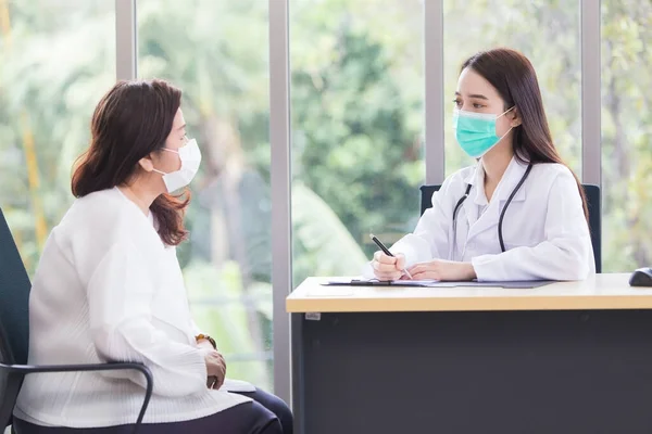 Asian elder woman consults with professional doctor about her symptom or health problem in examination room at hospital.