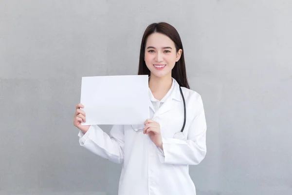 医療用のコートを着て 医療の概念に何かを提示するために白い紙を示してアジアの専門医の女性 — ストック写真