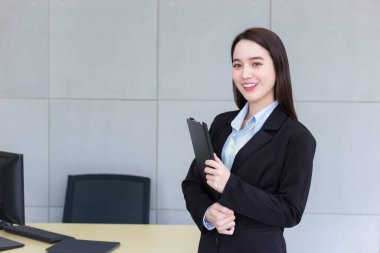 Ofisteki güzel bayan ayakta ve mutlu bir şekilde gülümsüyor. Evden çalış..