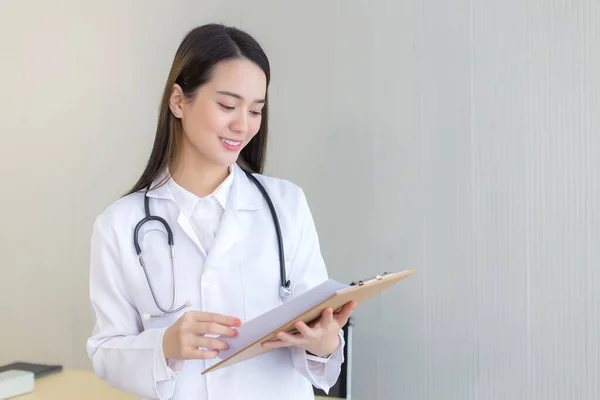 亚洲专业女医生检查病人的报告文件 以计划下一步的治疗 在医院工作时 她看着手中的剪贴板 — 图库照片