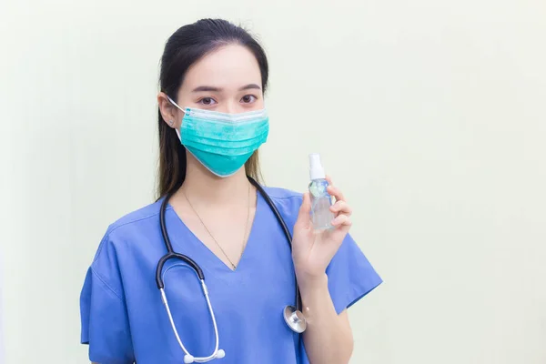 青い制服を着たアジアの女性医師が健康診断を待っている間 マスクを着用し アルコールスプレーを保持し 手を洗う コロナウイルス防止コンセプト — ストック写真