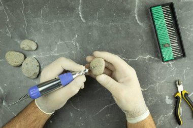 Bir adam kalıpları ve yazıları taşa kazıyor. Özel ev işleri. Evde ellerinle para kazanma fikri.
