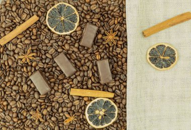 Kahve çekirdekleri ve çikolatalar arka planda mesajlaşmak için kullanılıyor. Çikolatalı kahve ve fındıklı tarçın. Kahve çekirdekleri üzerinde çikolata.