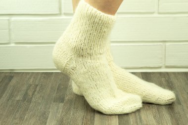 Beyaz ipliklerden el yapımı çoraplar, yakın plan tığ işi çoraplar. Örgü çoraplı bir kızın bacaklarının yakın plan fotoğrafı. İş fikri, hobi için para kazanmak. Yararlı karantina becerileri