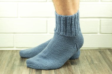 El yapımı çoraplar, sıcak ve kendi kendine ördüğün çoraplar. Örgü çoraplı erkek bacaklarının yakın plan fotoğrafı. İş fikri, hobi için para kazanmak. Yararlı karantina becerileri