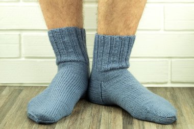 El yapımı çoraplar, sıcak ve kendi kendine ördüğün çoraplar. Örgü çoraplı erkek bacaklarının yakın plan fotoğrafı. İş fikri, hobi için para kazanmak. Yararlı karantina becerileri