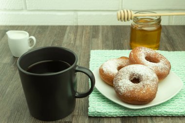 Taze pişmiş çörekler pudra şekerli ve bal ile kahve. Pudra şekerli çörek ve ballı kahve. Mesaj için yer var..