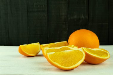 Portakal, ahşap arka planda küçük takozlar ve metin için boşluk şeklinde kesilir. Ahşap arka planda portakal dilimleri. Metin için boş alan