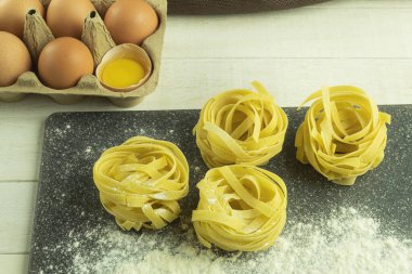 Ahşap arka planda yumurtalı erişte ve mesaj için yer var. Ahşap bir masada un ve yumurtadan ev yapımı erişte yapmak. Metin için boşluk olan kenar görünümü