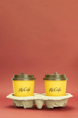 Varşova, Polonya - 25 Mart 2021: Bir stantta iki kağıt kahve fincanı. Kahverengi bir McDonald 's tepsisinde iki portakallı tek kullanımlık bardak var. Arkaplan ve kopyalama alanı