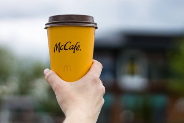 Varşova, Polonya - 19 Mayıs 2021: bir kadının elinde kağıt bardak McDonald 's kahvesi. McDonalds fast food restoranından elinde bir fincan McCafe kahvesi tutan bir kız.