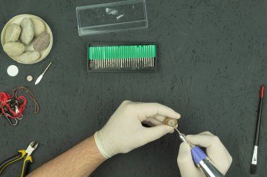 Bir oyma makinesiyle taş işleme. Adamın elleri bir oymacı tarafından taşın üzerine kazınmış. Taş ve metale profesyonel oyma. Metin için yeri olan arkaplan