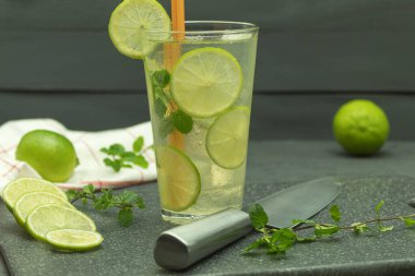 Limonlu, buzlu ve naneli soğuk içecek. Ev yapımı ferahlatıcı limonata, arka planda mesaj için yer var. Siyah arkaplanda buzlu mojito kokteyli.