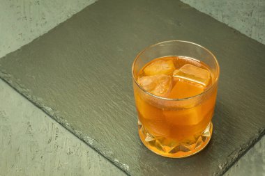 Alkollü içecek ve buzlu bir bardak. Kopyalama uzayı olan bir taş standında selobant. Buzlu viski. Arka plan ışıklandırması ve bir bardak alkollü içki. Metin için alanı olan arkaplan