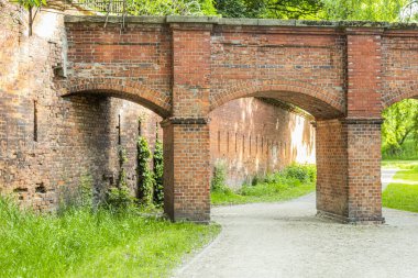 Eski bir kalede kemerli bir kırmızı taş köprü. Kaleye bağlı bir kemerle köprünün görüntüsü