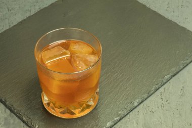 Alkollü içecek ve buzlu bir bardak. Kopyalama uzayı olan bir taş standında selobant. Buzlu viski. Arka plan ışıklandırması ve bir bardak alkollü içki. Metin için alanı olan arkaplan