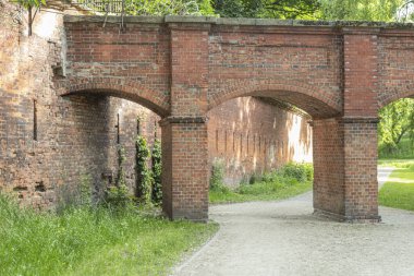 Eski bir kalede kemerli bir kırmızı taş köprü. Kaleye bağlı bir kemerle köprünün görüntüsü
