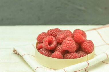 Ahududu, ahşap arka planda taze ve suludur. Ahşap bir masada sepetin içinde olgun ahududular. Yakın plan, metin için alanı olan arkaplan. Hasat konsepti