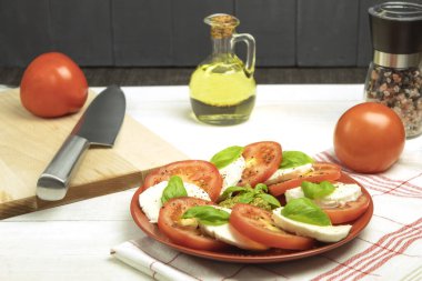 Ahşap arka planda bir tabakta Caprese salatası. Taze domates ve fesleğen yapraklı mozzarella peyniri. Ahşap bir masada salata. Kopyalama alanı olan üst görünüm