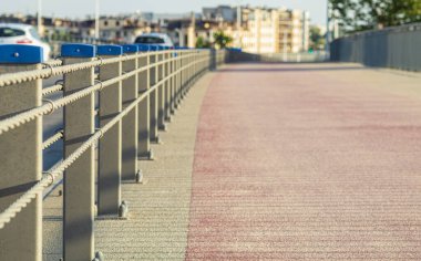 Koşu parkuru at arabasından çitle çevrilmiş. Sütunlarla eskrim ve otobanın kaldırımlarından bir kablo. Yakın plan. Açık bir gün, güneşli bir ışık. Metin için boşluk