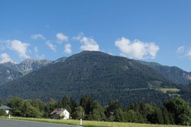 Güneşli ve açık bir günde bulutlu dağların ve gökyüzünün manzarası. Sabah, dağlar ve dağların tepesindeki kıvrımlı bulutlar