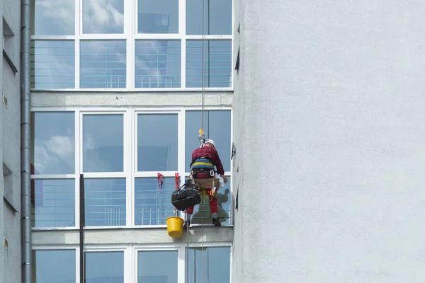 A man washes windows in a multi-storey building. Professional window cleaning. A climber washes a window on a skyscraper, bottom view. Background with copy space