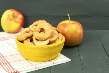 Bir kasede olgun elmalar ve kurutulmuş elmalar. Elma hasat ve kurutma. Masanın üzerinde kurumuş elma dilimleri var. Metin için alanı olan arkaplan
