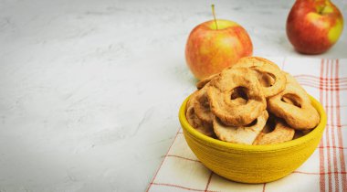 Bir kasede olgun elmalar ve kurutulmuş elmalar. Elma hasat ve kurutma. Masanın üzerinde kurumuş elma dilimleri var. Metin için alanı olan arkaplan