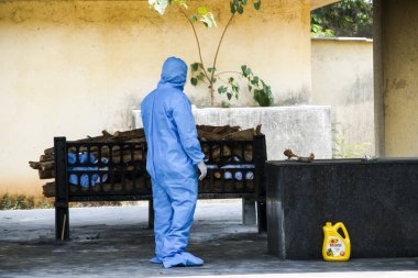 Vasai, Maharashtra, Hindistan - 04 Mayıs 2021: Bir belediye çalışanı, bir krematoryumda yakılan Covid-19 kurbanını yakmak için Kişisel Koruyucu Ekipman (PPE) takıyor. 