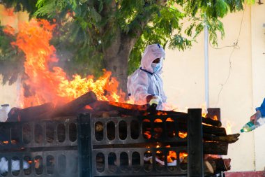 Vasai, Maharashtra, Hindistan - 04 Mayıs 2021: Bir belediye çalışanı, bir krematoryumda yakılan Covid-19 kurbanını yakmak için Kişisel Koruyucu Ekipman (PPE) takıyor. 