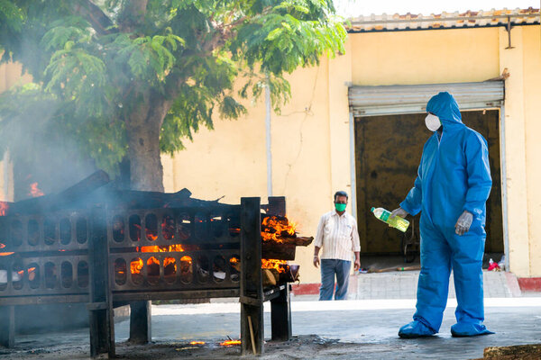 Vasai, Maharashtra, India - May 04, 2021: A municipal worker wears a Personal Protective Equipment kit (PPE) to cremate a Covid-19 victim at a crematorium. 