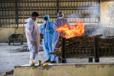 Vasai, Maharashtra, Hindistan - 04 Mayıs 2021: Kişisel Koruyucu Malzemeler (PPE) giyen belediye çalışanları, bir krematoryumda Covid-19 kurbanı yaktı. 