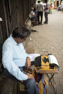Mumbai, Hindistan / 5 Ekim 2018: Yürüme yolunda yasal belge yazmak için klasik daktilo kullanan bir daktilocu.  