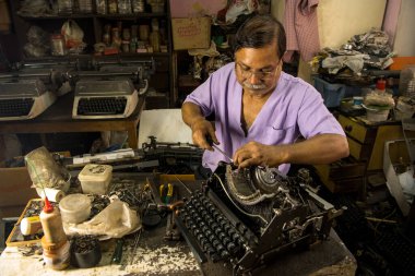 Mumbai, Hindistan / 29 Eylül 2018: Bir teknisyen atölyede eski bir daktiloyu tamir etti.
