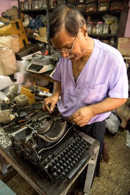 Mumbai, Hindistan / 29 Eylül 2018: Bir teknisyen atölyede eski bir daktiloyu tamir etti.