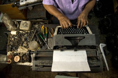 Mumbai, Hindistan / 29 Eylül 2018: Bir teknisyen atölyede eski bir daktiloyu tamir etti.