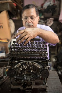 Mumbai, Hindistan / 29 Eylül 2018: Bir teknisyen atölyede eski bir daktiloyu tamir etti.