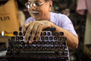 Mumbai, Hindistan / 29 Eylül 2018: Bir teknisyen atölyede eski bir daktiloyu tamir etti.