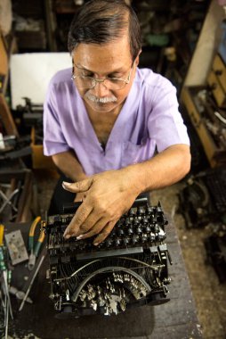 Mumbai, Hindistan / 29 Eylül 2018: Bir teknisyen atölyede eski bir daktiloyu tamir etti.