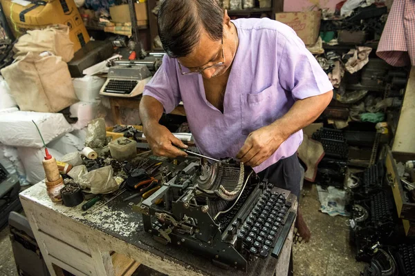 Mumbai, Hindistan / 29 Eylül 2018: Bir teknisyen atölyede eski bir daktiloyu tamir etti.
