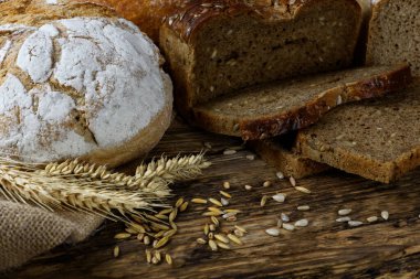Tahta bir masada buğday, ayçiçeği ve çavdar taneli koyu ekmekler..