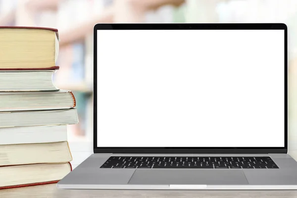 Template for online education - stocks of books next to the laptop with a blank white screen on a desk