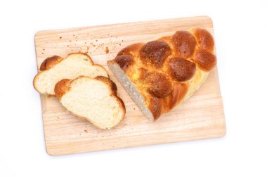 Zopf, challah, etek ya da brioche adındaki geleneksel bir maya ekmeğinin ahşap bir kesim tahtasının üzerinde izole edilmiş ve beyaz bir zemin üzerinde izole edilmiş üst görüntüsü..
