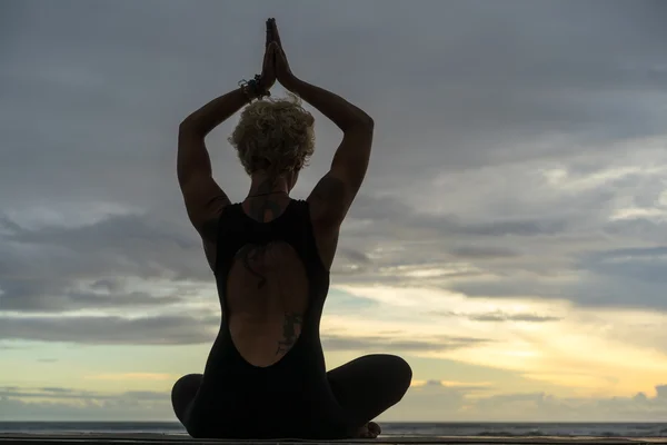 Mulher praticando ioga ao pôr do sol — Fotografia de Stock